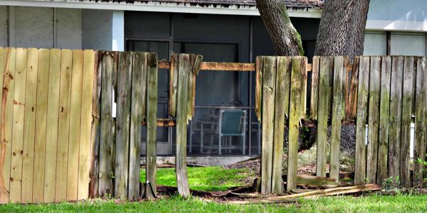 A broken wooden fence in front of a house.