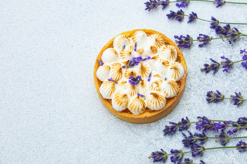 A beautifully crafted tart features meringue peaks adorned with lavender sprigs.
