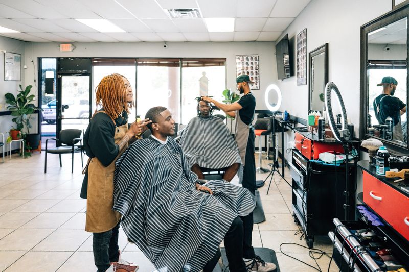 Wide shot of Barbers working on client's hair