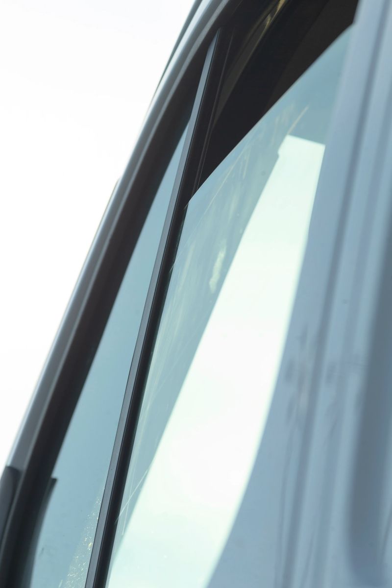 The stunning closeup image of a cars window highlights the clarity of the glass and elegant framing, showcasing the vehicles transparency, sleek design, and modern aesthetics