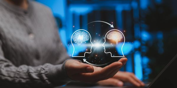 Two illuminated brain icons connecting above a person's hand.