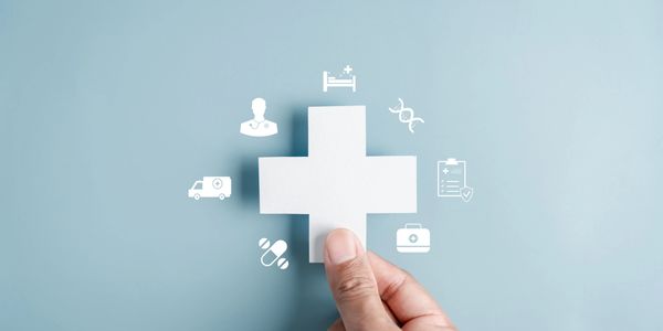 Hand holding a white medical cross with health icons.