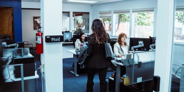 Woman talking to two workers in an office.