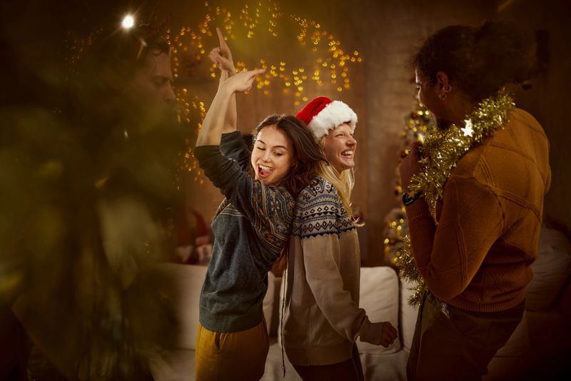 Young cheerful couples having fun while dancing during a party on New Year's at home.