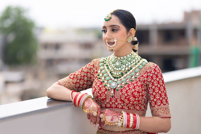 Portrait of very beautiful young Indian bride in luxurious bridal costume with makeup and heavy jewellery outdoors