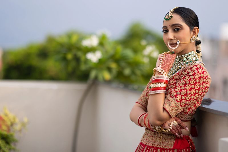 Portrait of very beautiful young Indian bride in luxurious bridal costume with makeup and heavy jewellery outdoors