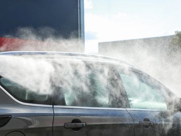 A black car being washed with water spray.