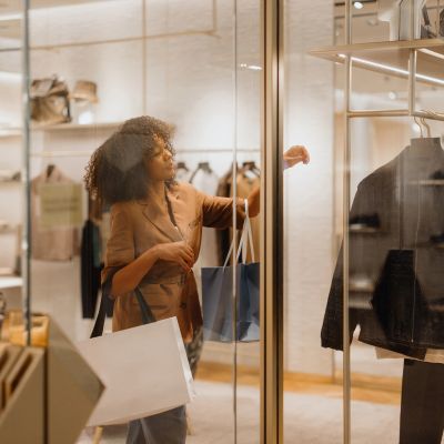 Woman shopping, carrying bags and looking at clothes in a store.