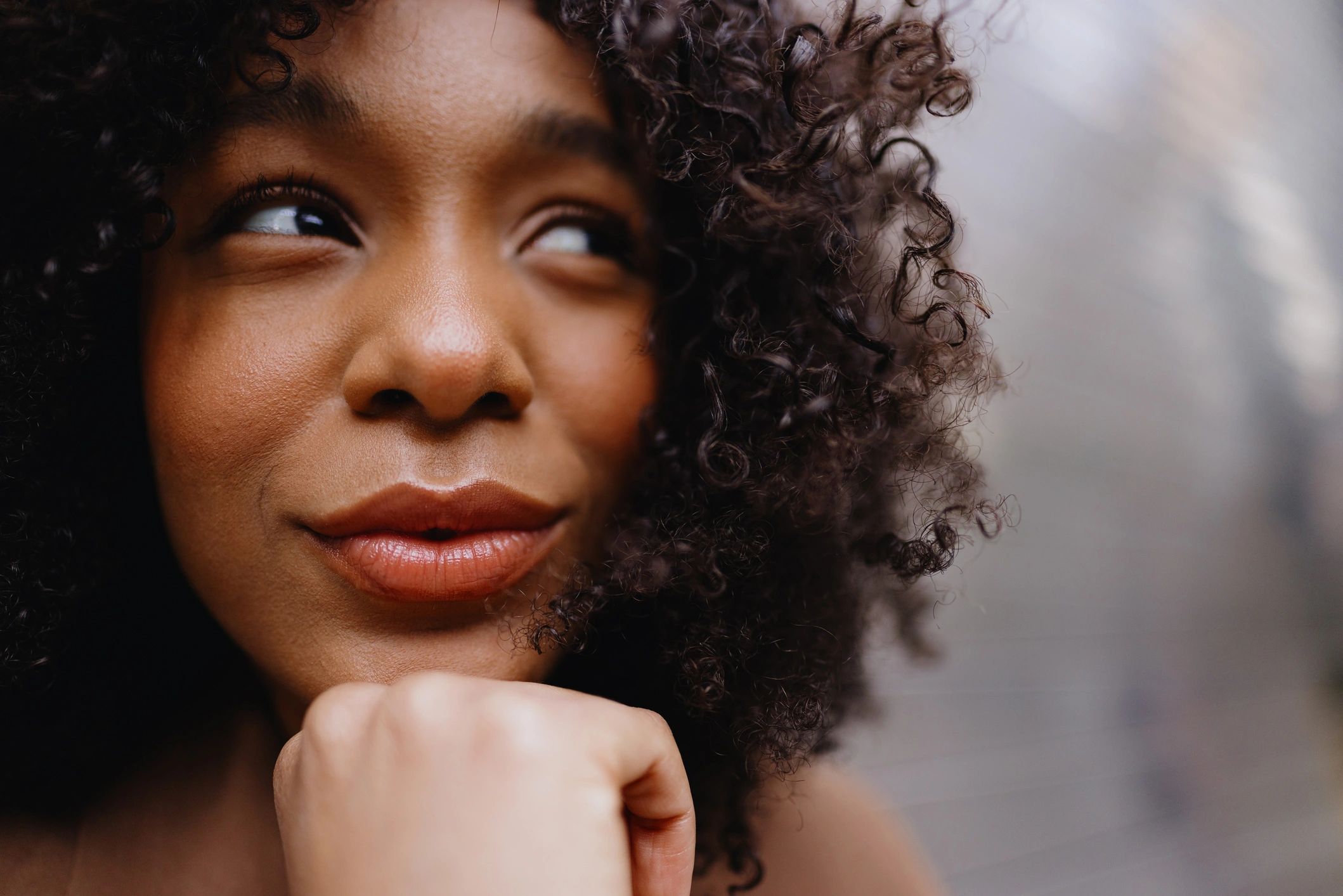 Close-up of a woman with curly hair and a thoughtful expression.