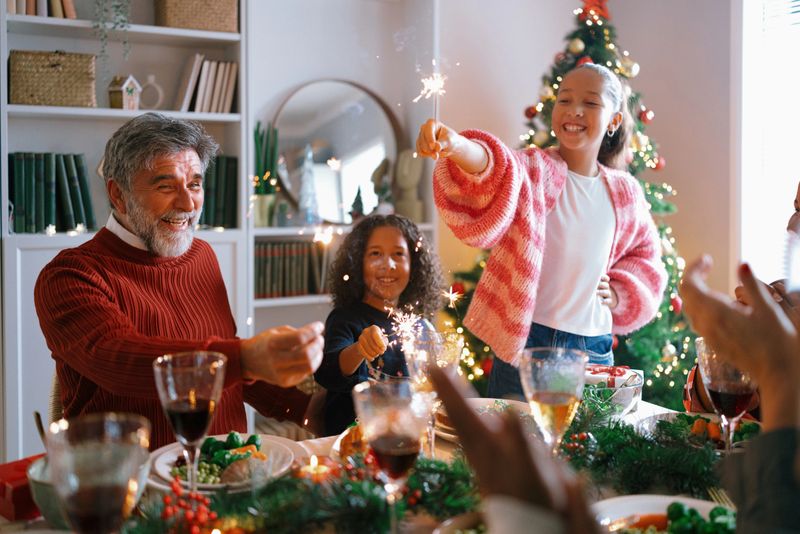 Multigenerational family holding sparklers and singing together, full of festive joy and energy.