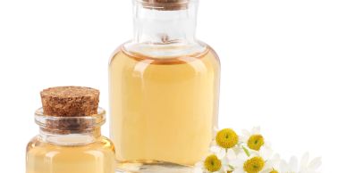 Two glass bottles with cork stoppers and chamomile flowers.