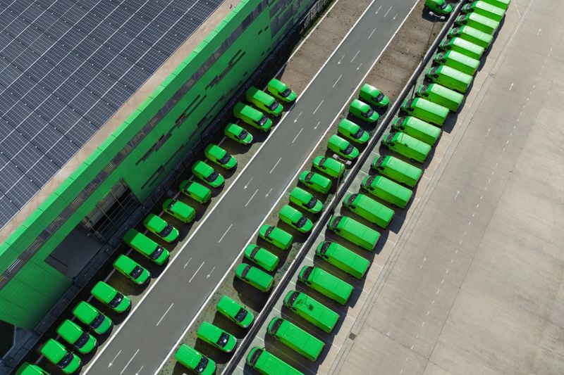 Delivery vans hub with solar panel on a roof. Fleet of green vehicles