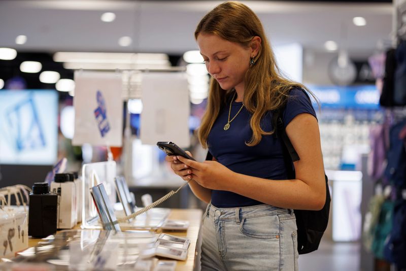 Teenage girl testing smartphone in electronics store
