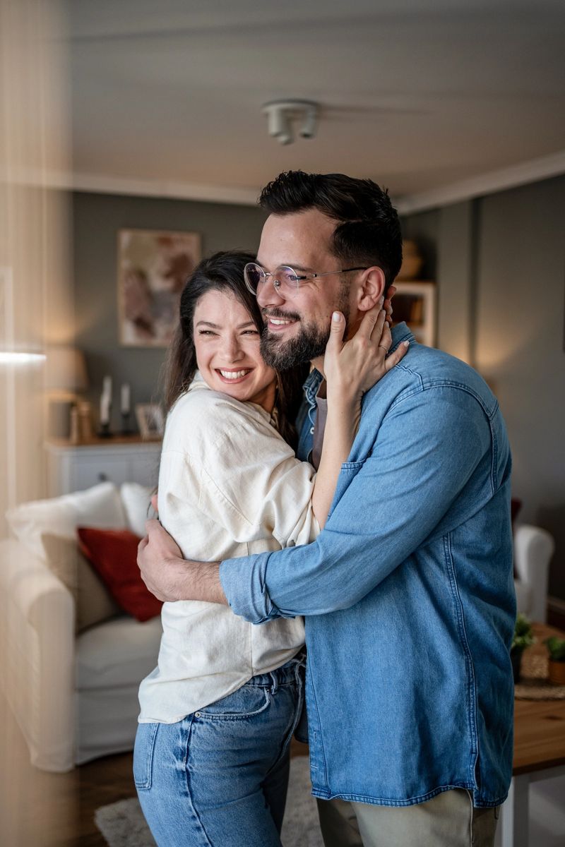 Young couple embracing in their cozy home, faces glowing with joy and love, radiating warmth and happiness in a moment of intimate connection and domestic bliss