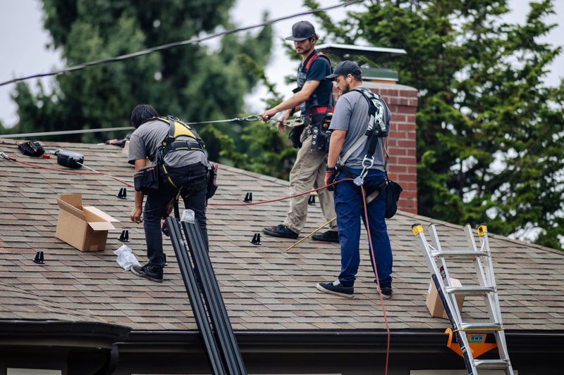 Professional engineers installing solar panels on roof of a residential home in Portland, Oregon, Pacific Northwest USA. Green energy concepts.