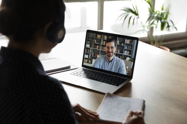 Person attending an online video call while taking notes.