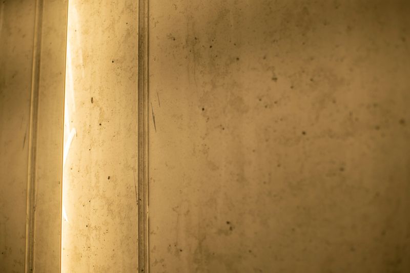 A detailed closeup shot of a concrete wall featuring a warm light shining softly through its rough surface, creating a striking visual effect