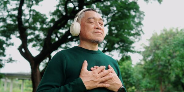 Man with headphones enjoying peaceful moment outdoors with eyes closed.
