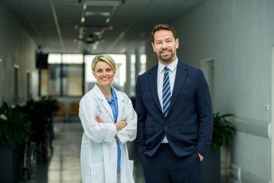 Smiling doctor and businessman standing in a corridor.