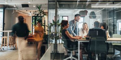 People collaborating around a table in a modern office space with glass walls.
