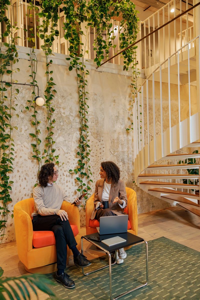 In a vibrant green workspace with modern decor, two professionals engage in an inspiring discussion about ideas
