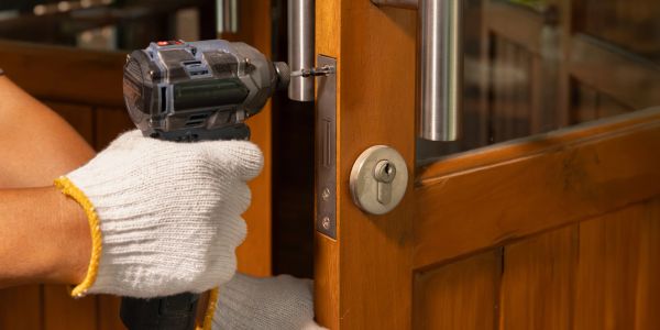 Person using a power drill to fix a wooden door.