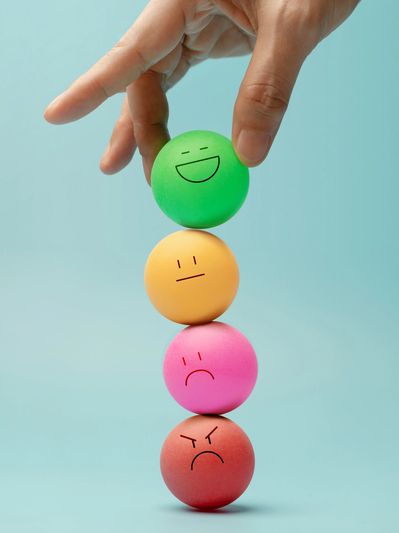 Hand balancing colorful balls with different facial expressions.