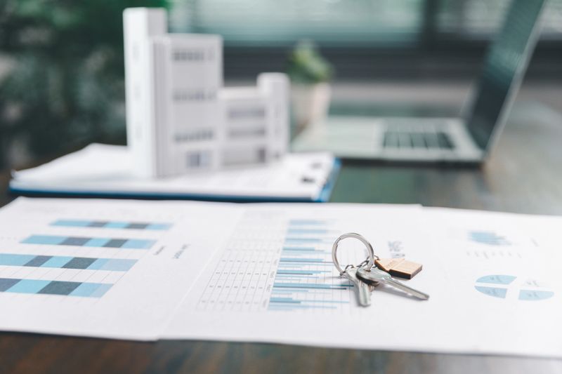 House model placed on table alongside coins, paperwork symbolizes real estate investment, property valuation, representing financial planning, mortgage options, market analysis in property business.