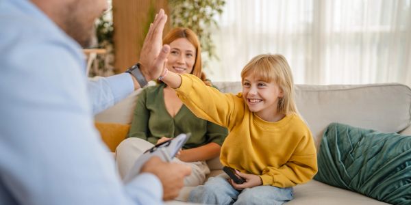 Child giving a high-five to an adult indoors.