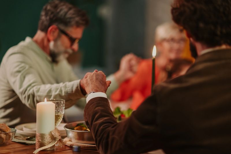 Family members holding hands and praying together, expressing gratitude before enjoying a festive christmas dinner at home