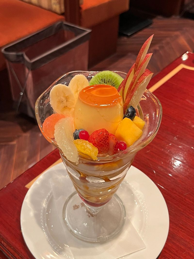 Creamy pudding à la mode topped with fresh fruits and a scoop of ice cream, offering a perfect harmony of smooth, sweet, and refreshing flavors in every elegant and delightful spoonful.