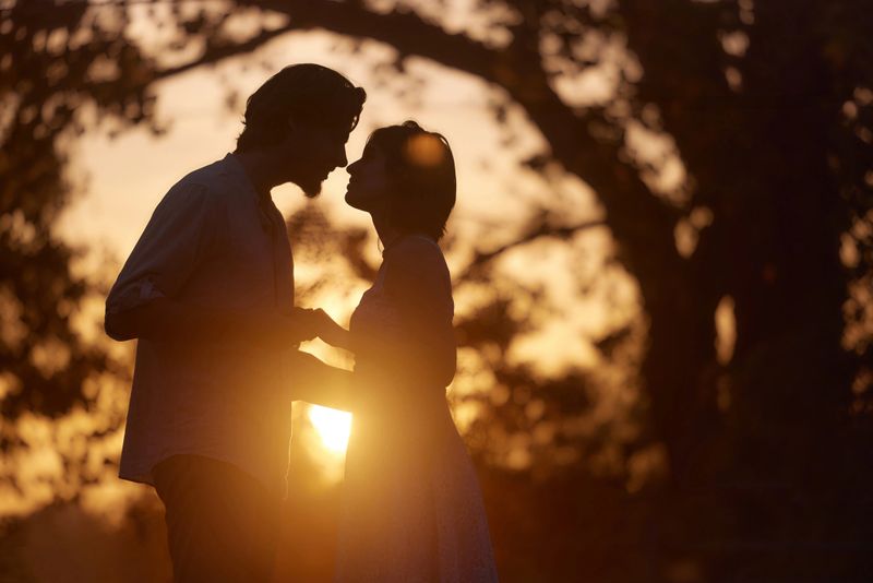 Affectionate couple kissing during romantic moment in nature at sunset. Copy space.