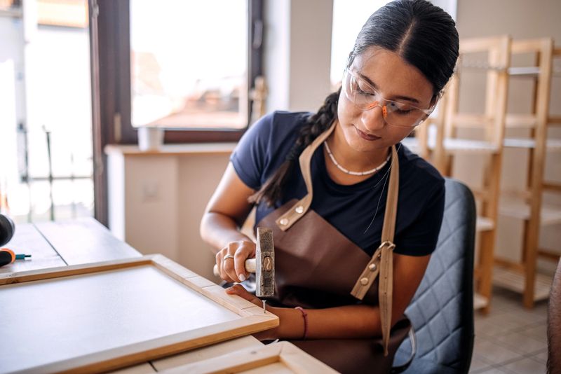 Young woman having her own business and working with wood in her carpentry workshop