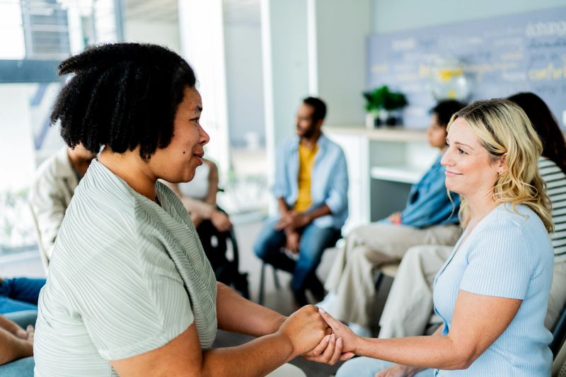 Mid adult woman comforting patient during group therapy session