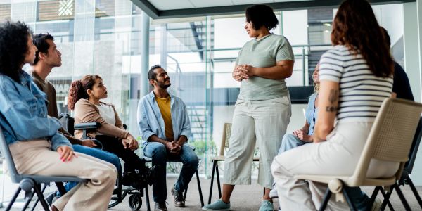 A group therapy session in progress with a standing facilitator.