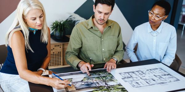 Three professionals discussing architectural plans at a table.