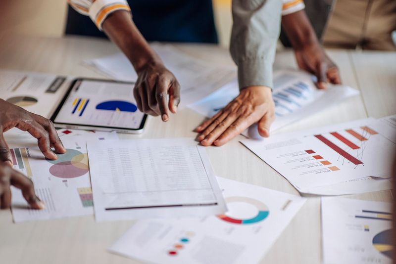 Group of professionals reviewing business charts and financial data on reports during a collaborative meeting, emphasizing teamwork and decision-making strategies