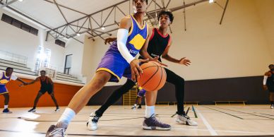 Two players compete for a basketball in a gym.