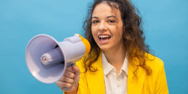 Excited woman in yellow jacket with megaphone.