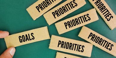 Pieces of cardboard labeled 'GOALS' and 'PRIORITIES' scattered on a green surface.