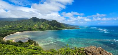 Scenic coastal landscape with clear blue waters and lush green mountains.