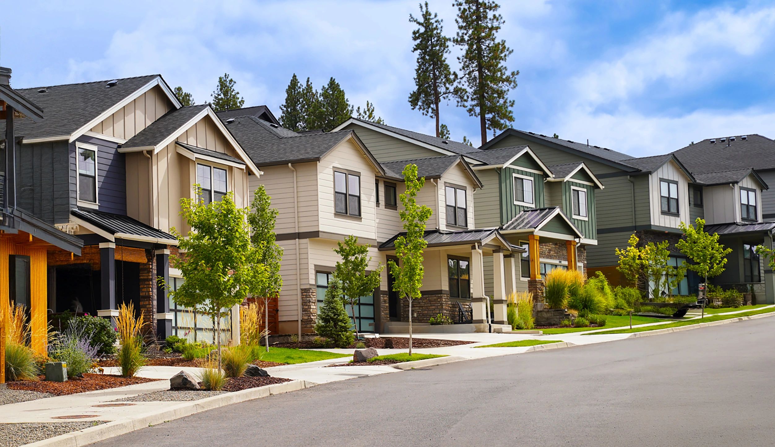 Modern suburban homes with lush greenery on a clear day.