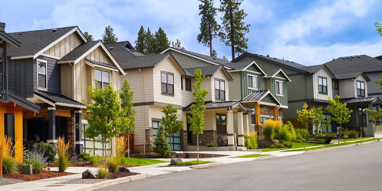 Row of modern suburban houses with well-maintained lawns and trees.