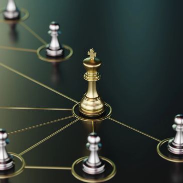 Golden king chess piece connected to silver pawns on black board.