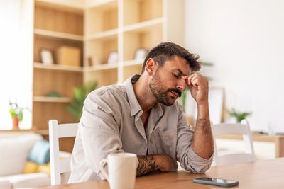 Man sitting tired at table with phone.