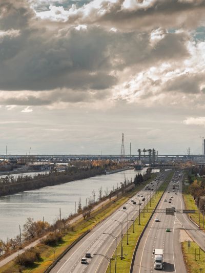 Vue d'une autoroute et d'un canal sous un ciel nuageux.