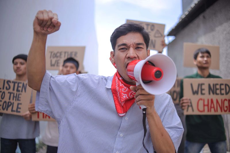 Determined Protestor With Megaphone And Raised Fist Demands Change During Demonstration