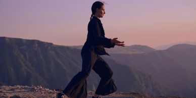 Person practicing Tai Chi at sunset on a mountain.