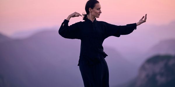 Woman practicing Tai Chi in nature, breathing deeply feeling energised.