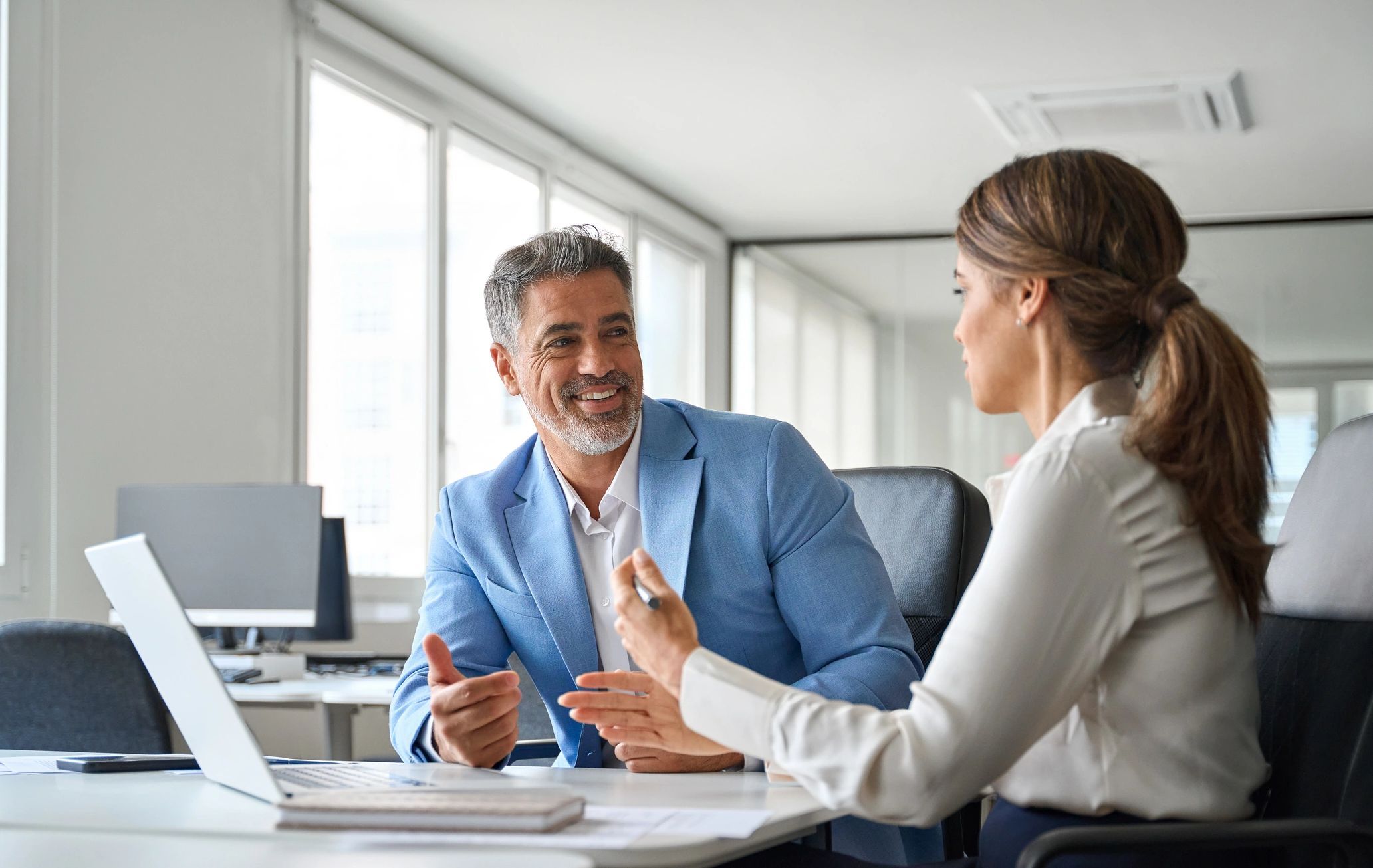 Two colleagues discussing work in a modern office.
